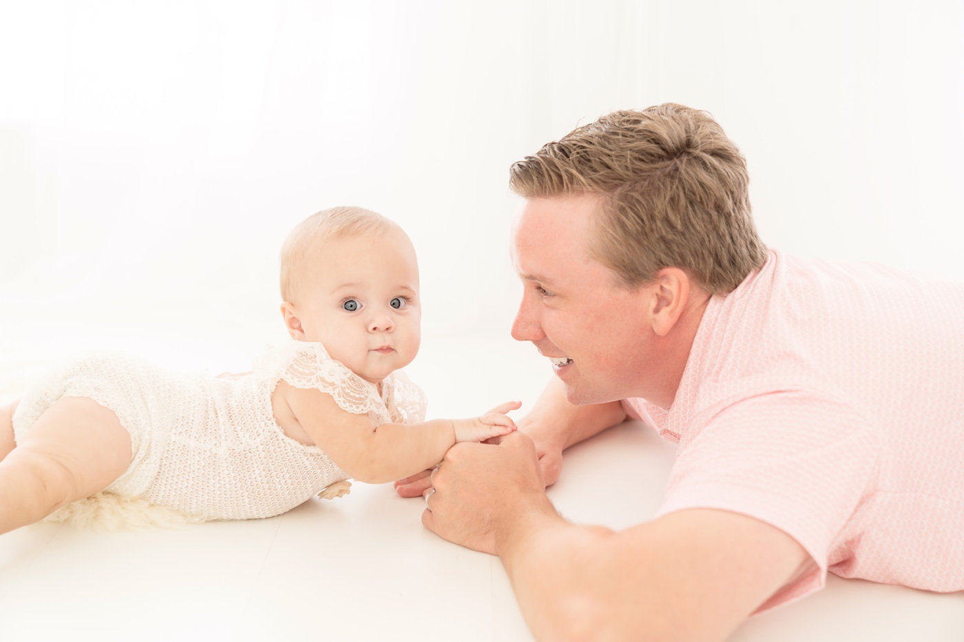 dad and baby being photographed in a white photography studio