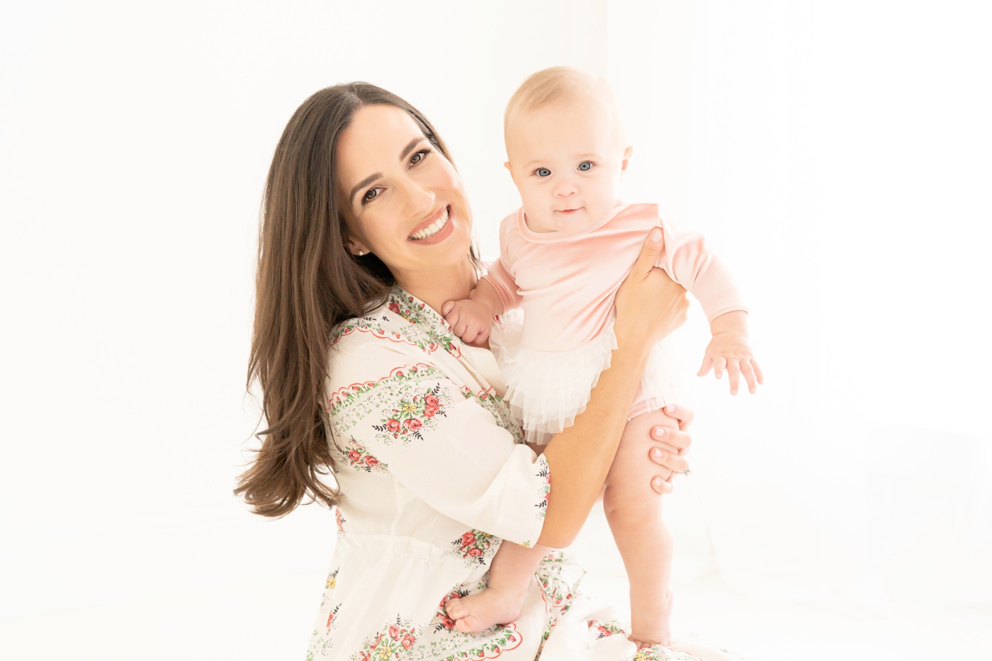 Mom and baby being photographed in a white photography studio