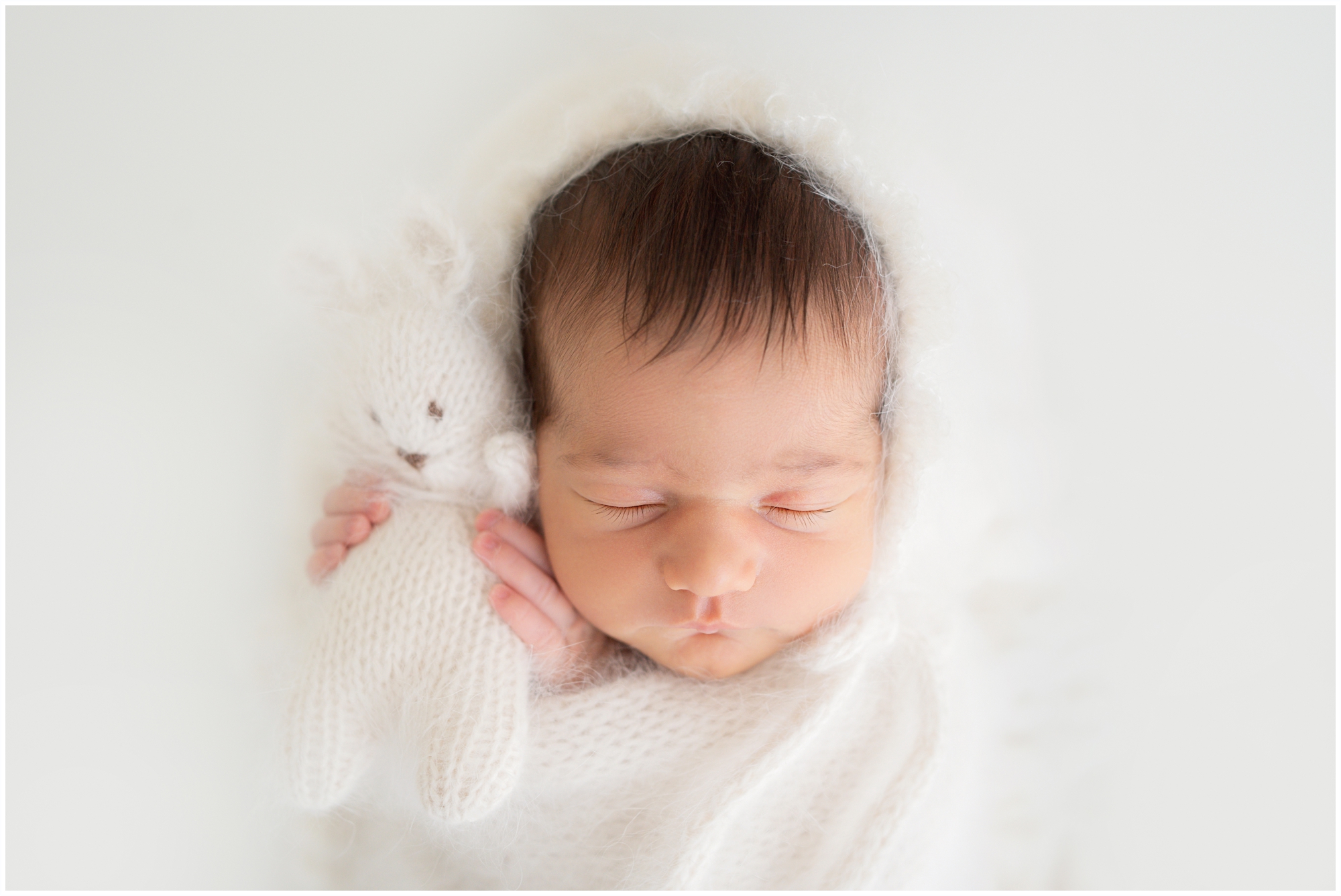 Brand new baby swaddled in white laying in a heart shaped bowl being photographed in Jupiter Fl studio