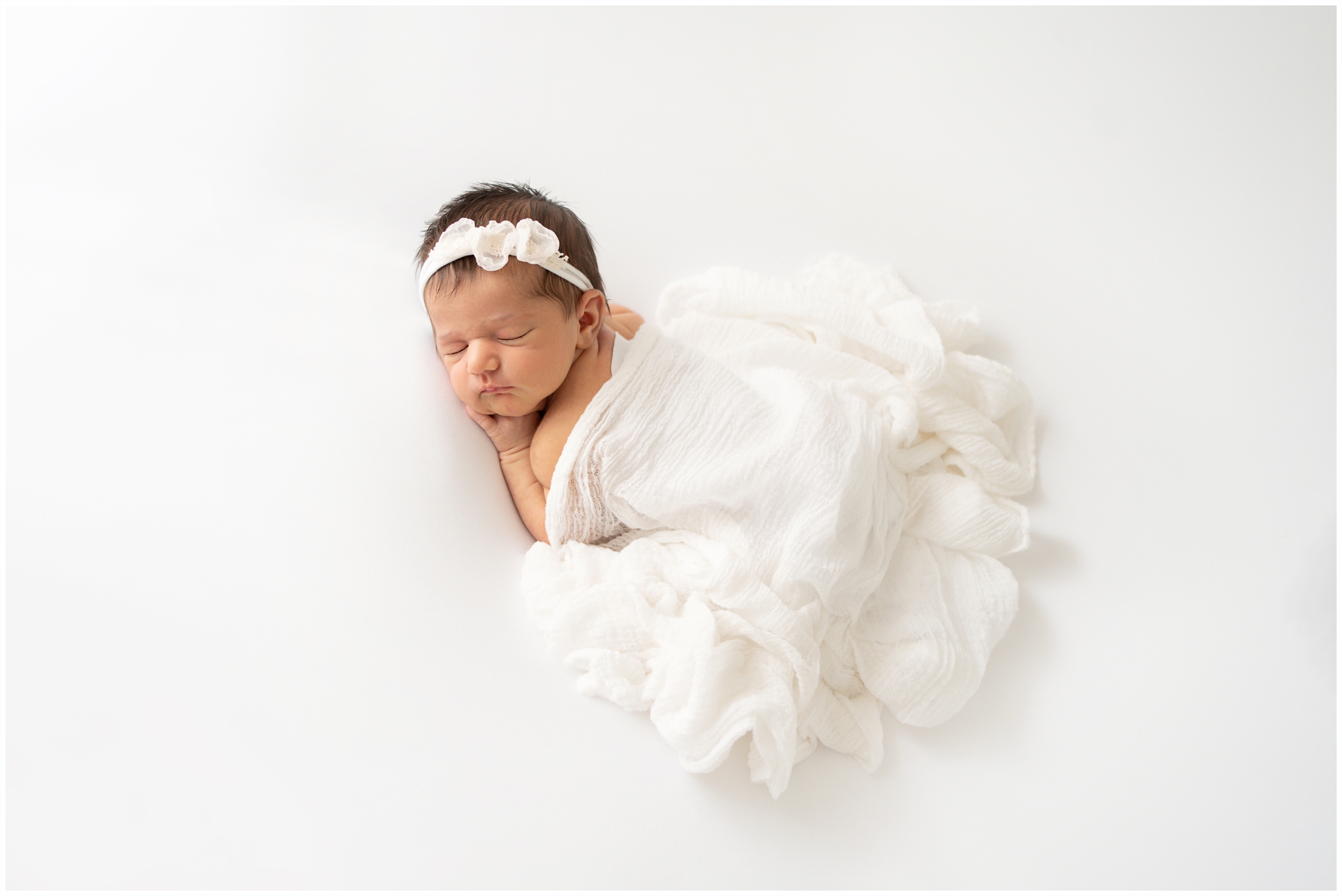 Brand new baby swaddled on white blanket being photographed in Jupiter Fl studio